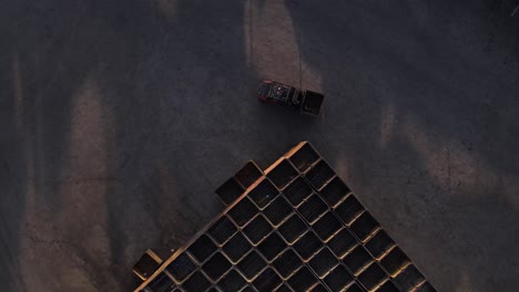 Drone-footage-of-a-forklift-driving-towards-pallets-which-the-driver-picks-up-with-the-forks-to-move