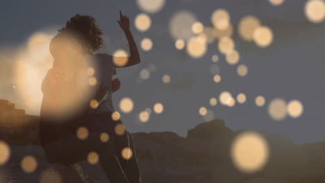 animation of light spots over biracial couple embracing at seaside