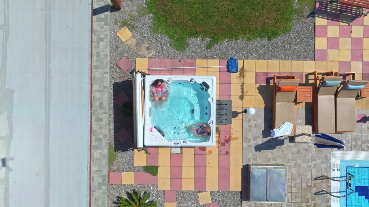 Birds eye aerial view of a mother and daughter relaxing in a jacuzzi, sunny day