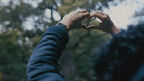 Cerrar-Mujer-Haciendo-Forma-De-Corazón-Con-Las-Manos-Feliz-Adolescente-Enamorada-Disfrutando-De-Un-Día-Frío-En-El-Parque-El-Concepto-Del-Día-De-San-Valentín