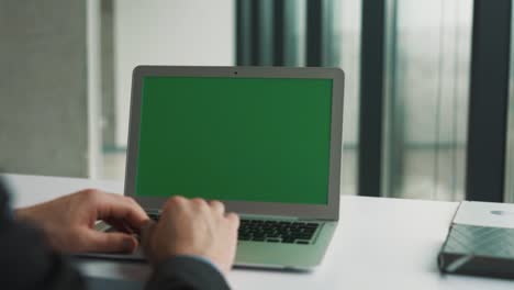manos masculinas volteando el panel táctil de una computadora portátil con una tecla de croma en la pantalla