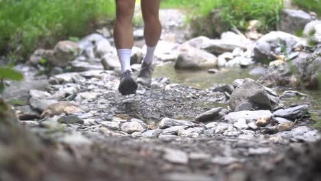 The-legs-of-a-young-person-hop-across-a-river,-jumping-from-stone-to-stone