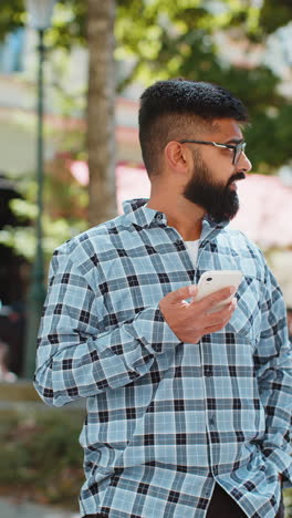 Indian-bearded-man-using-smartphone-typing-text-messages-in-social-media-application-online