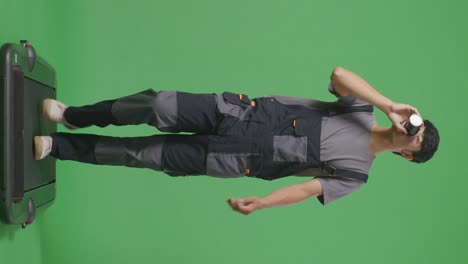 cuerpo lleno de hombre asiático trabajador bebiendo café mientras caminaba en el estudio de fondo de la pantalla verde