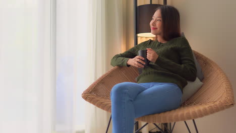 beautiful smiling asian woman enjoy cup of coffee on modern armchair