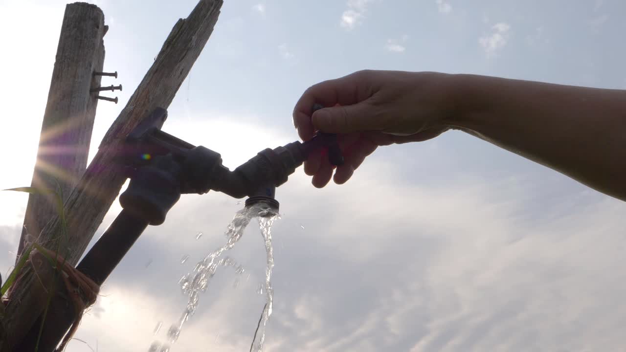 농민 필드 중간 샷에서 구불 구불 한 수도꼭지 탭을 돌리는 손