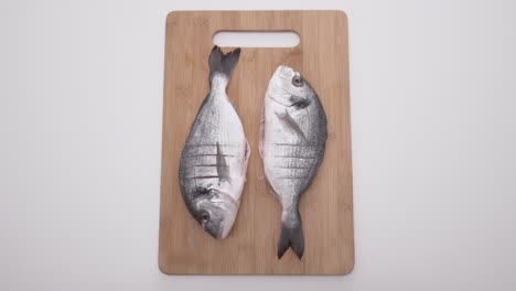 two raw sea bream on a wooden cutting board