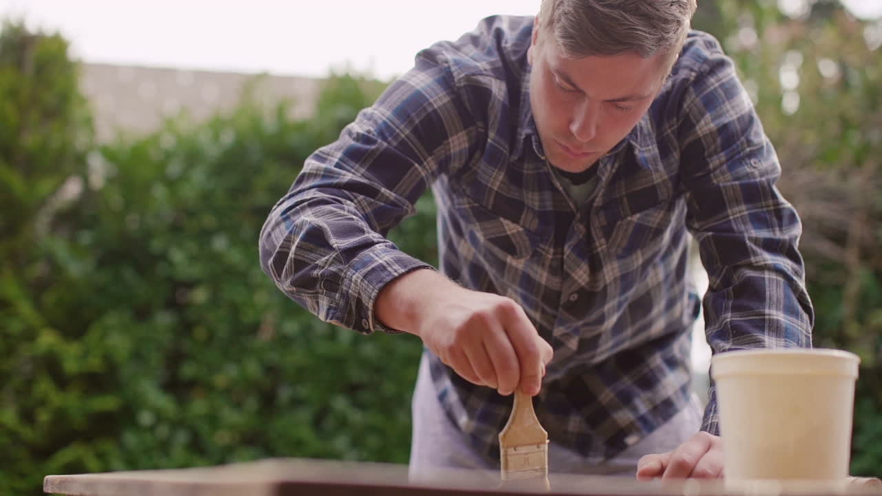 Man schildert een houten tafel in de tuin
