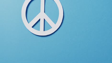 Close-up-of-white-peace-sign-and-copy-space-on-blue-background