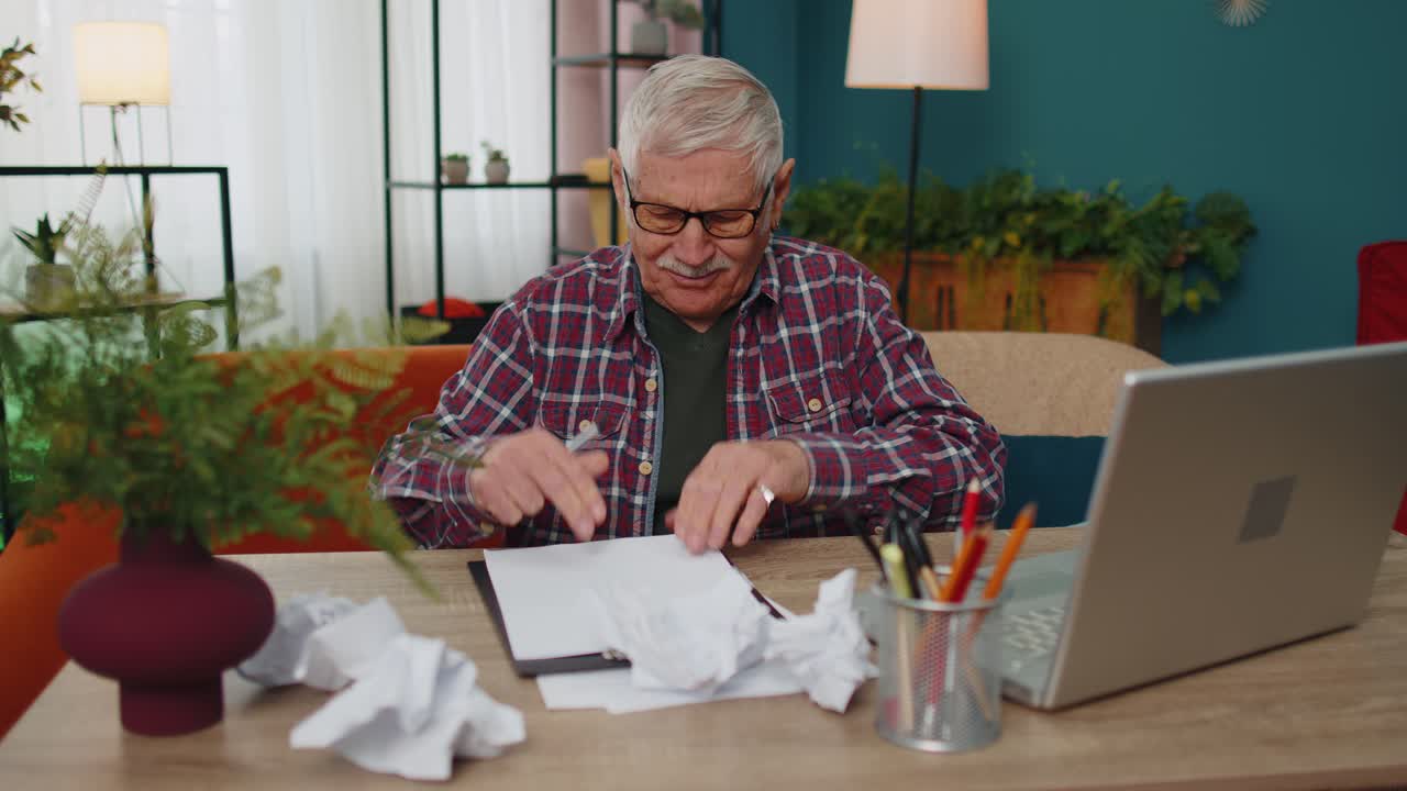 Grandfather working on laptop man writing on paper sheet getting angry crumpling it throwing away