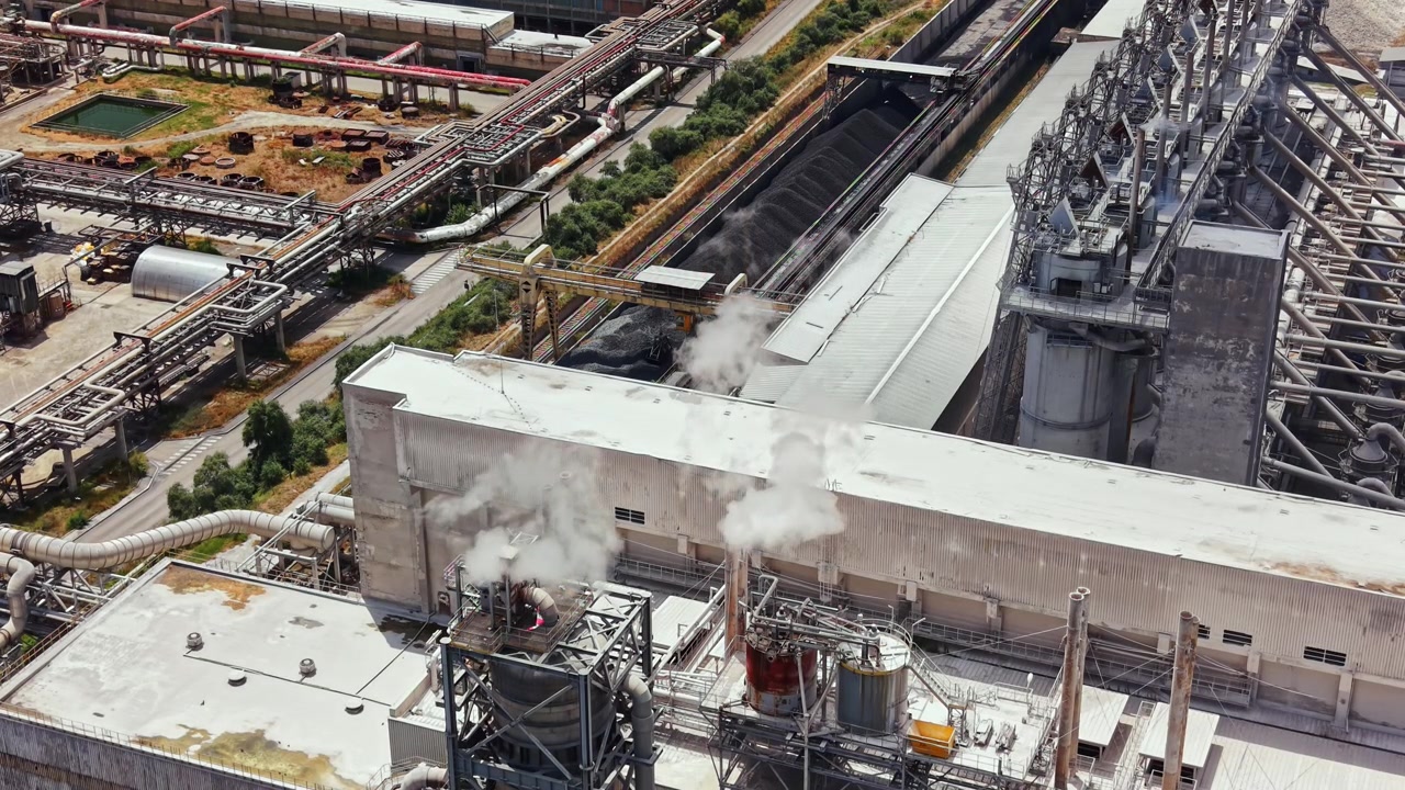 Industrial site with smoke and machinery during daytime in a busy area