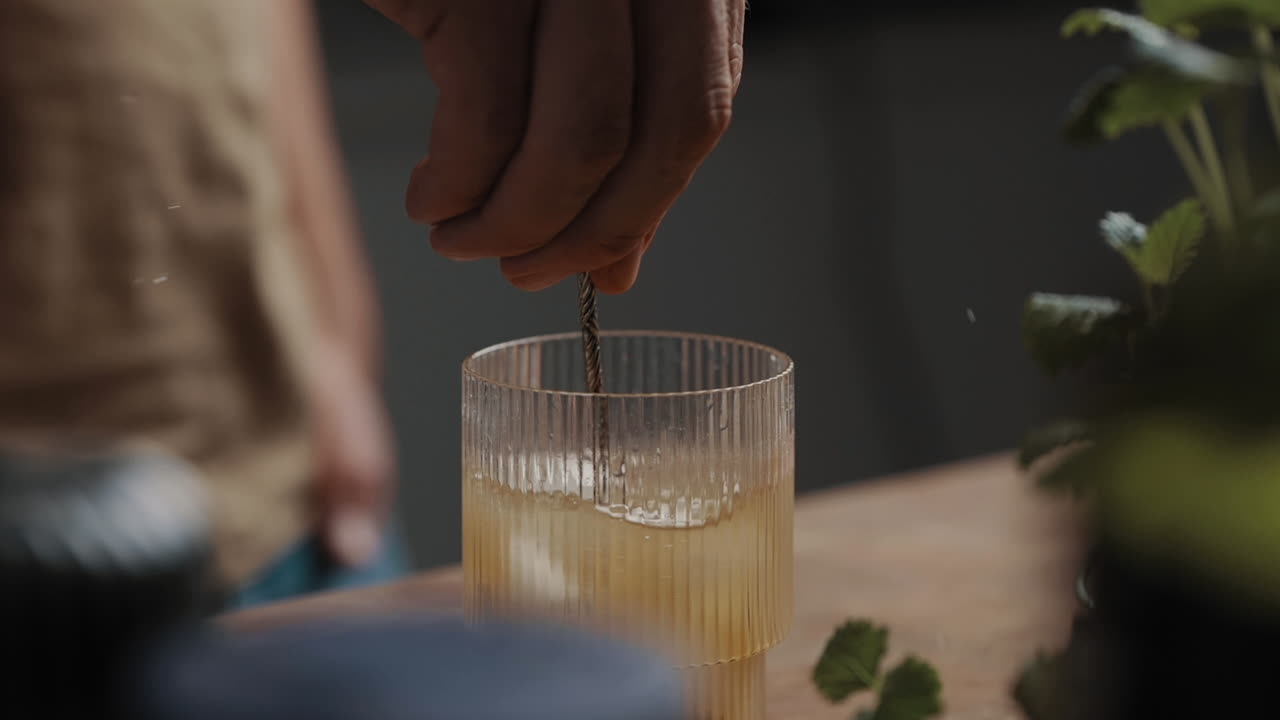 Young Male stirring fresh mixed cocktail in a drinking glas  4K Slow Motion Close Up