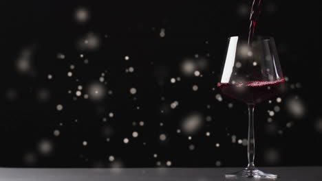 composite of glass of red wine over spots of light on black background