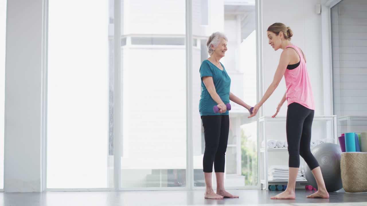 피트니스 강사 가 고령 여성 을 돕고 있다