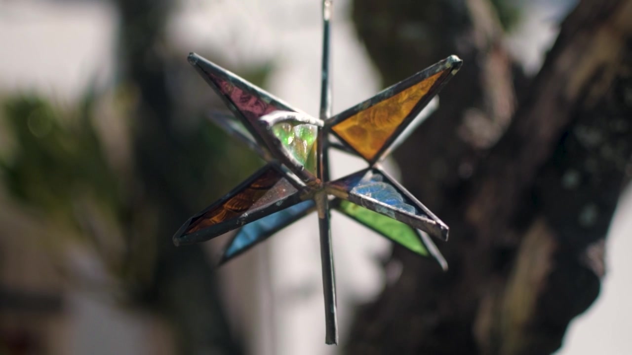 Glass star ornament hanging with the tree on the background