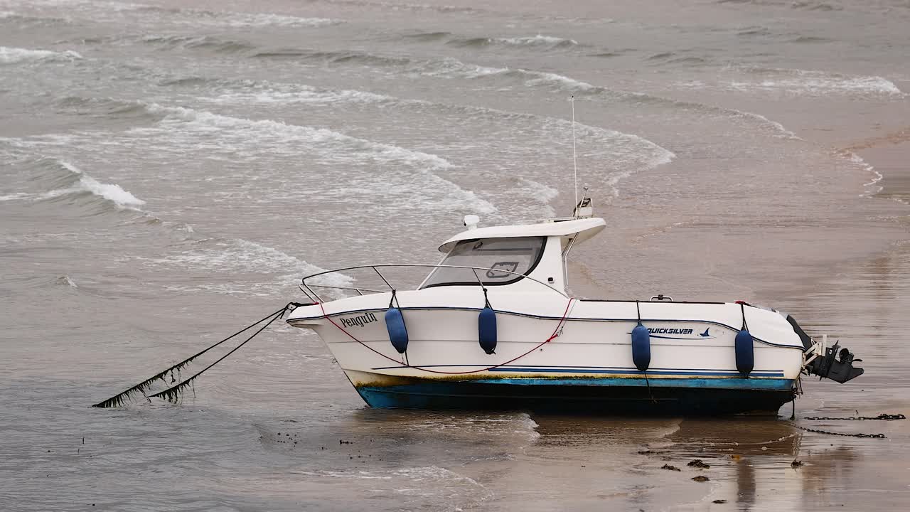 barco anclado en la playa con olas en el fondo