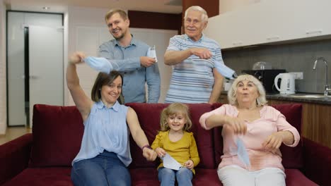 a family celebrates together in their living room, throwing their masks in the air