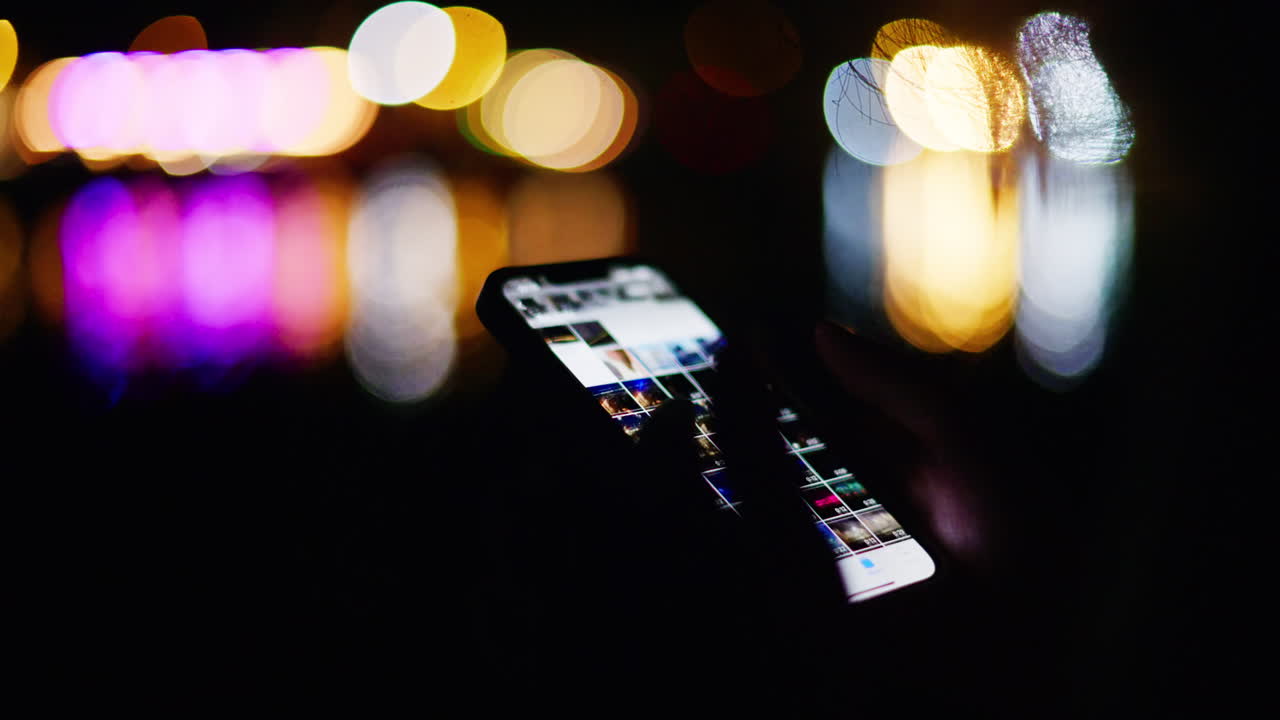 Woman scrolling on her phone on the beach at night