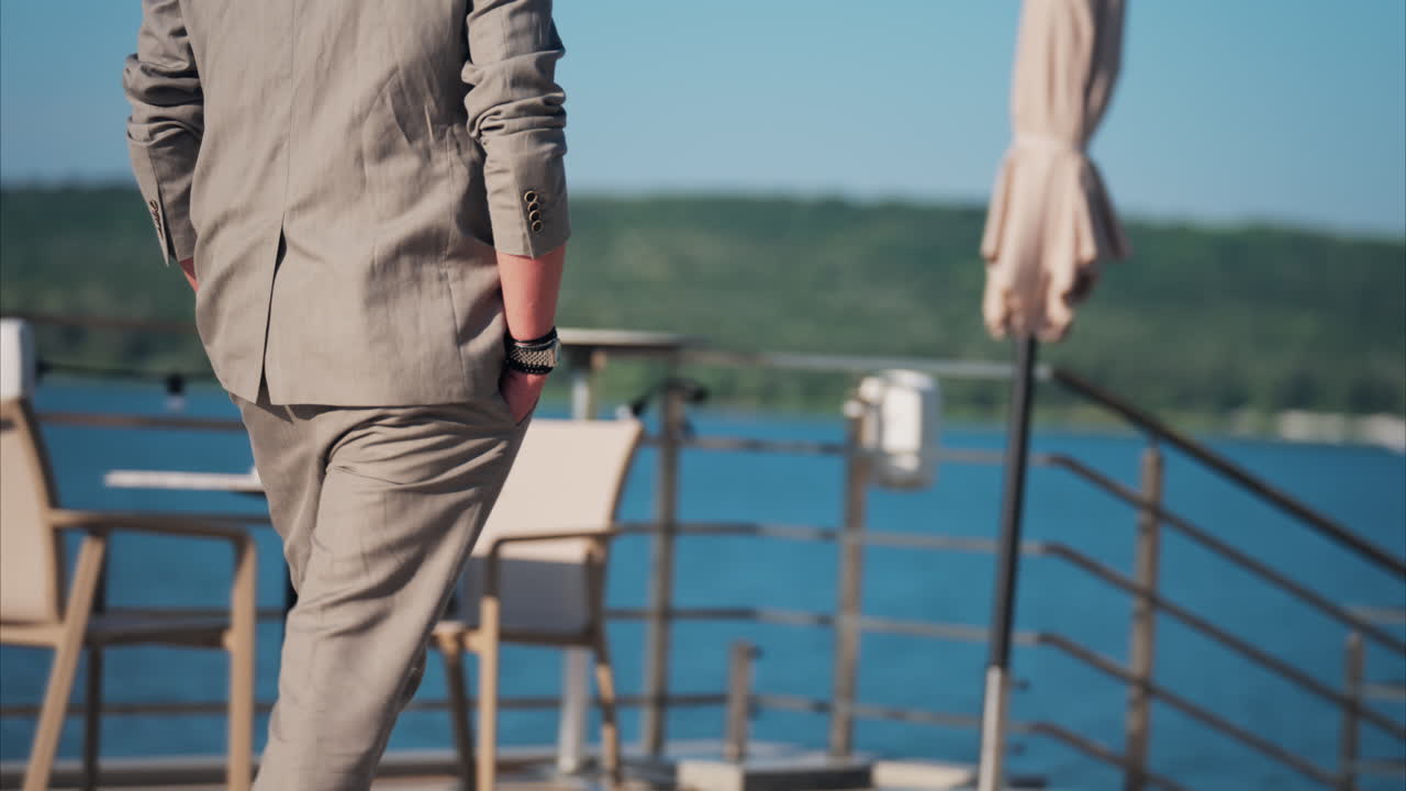 Man in beige suit walking past patio umbrellas on sunny terrace