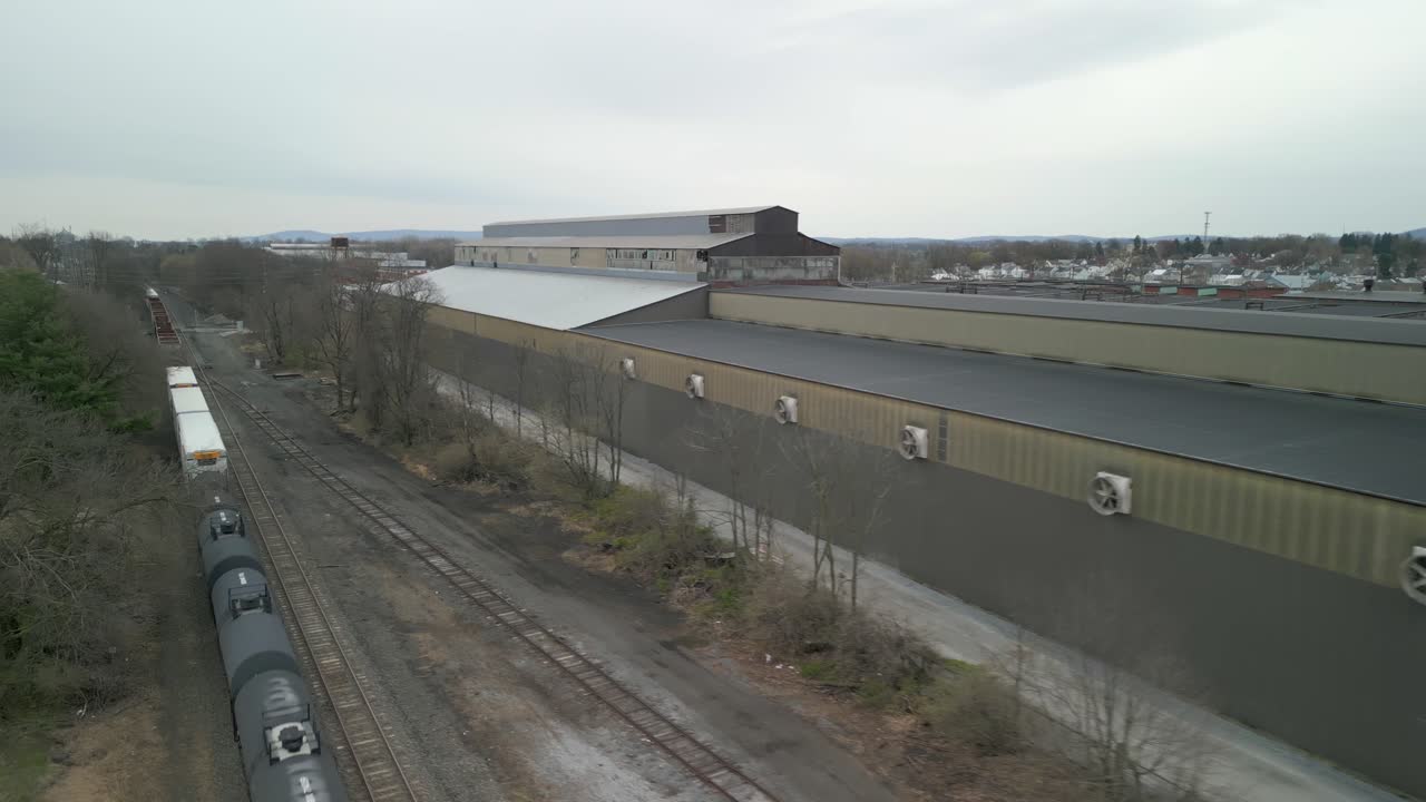 воздушный взгляд на поезд, проезжающий через массивный промышленный объект