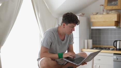 hombre trabajando en una computadora portátil en la cocina