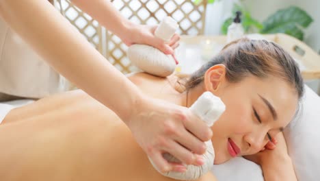 woman receiving a traditional herbal back massage at a spa