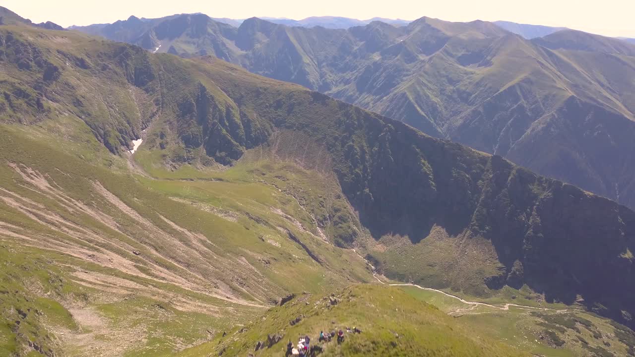 los excursionistas llegan a la cima de una montaña y son recompensados con una vista impresionante del paisaje escarpado, las montañas y el valle debajo