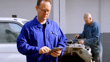 mechanic looking at camera while using digital tablet 4k