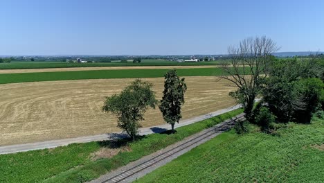 a wide view captures lush green crop fields bordered by a railway track