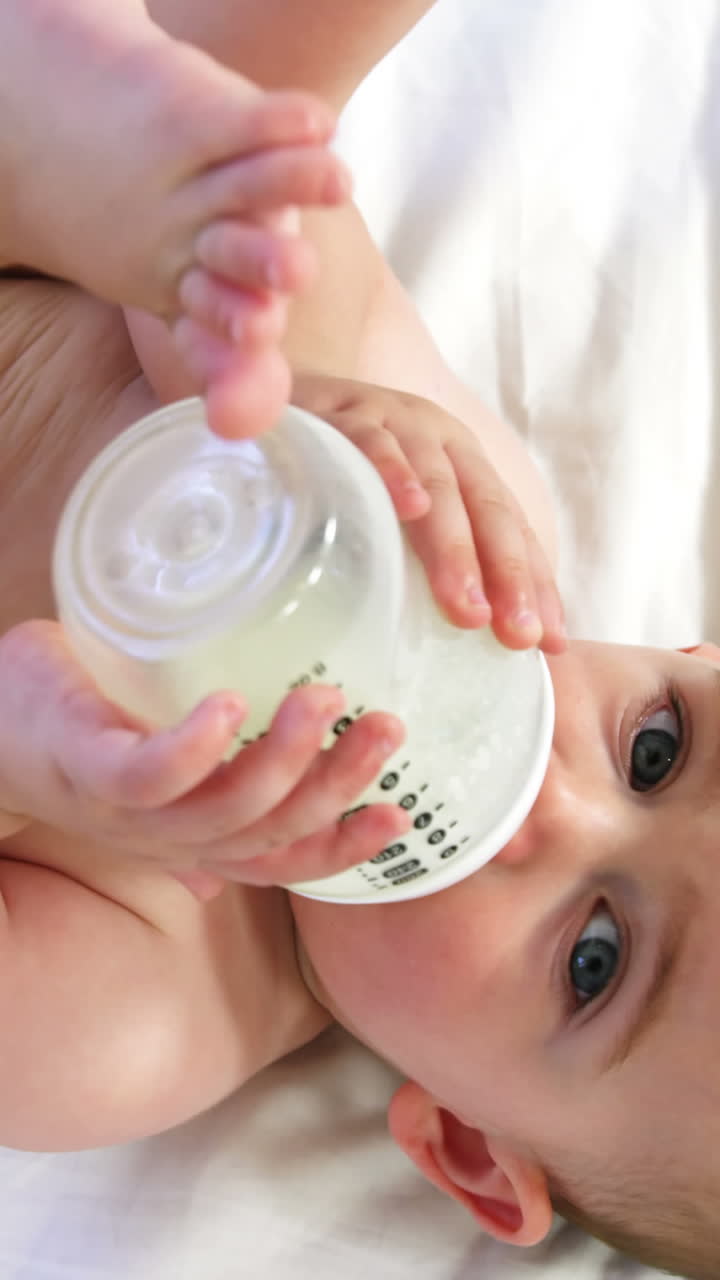 Bebè adorabile sdraiato che beve dal suo biberon