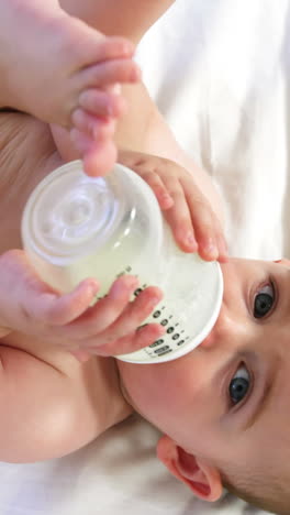 cute baby lying and drinking his baby's bottle