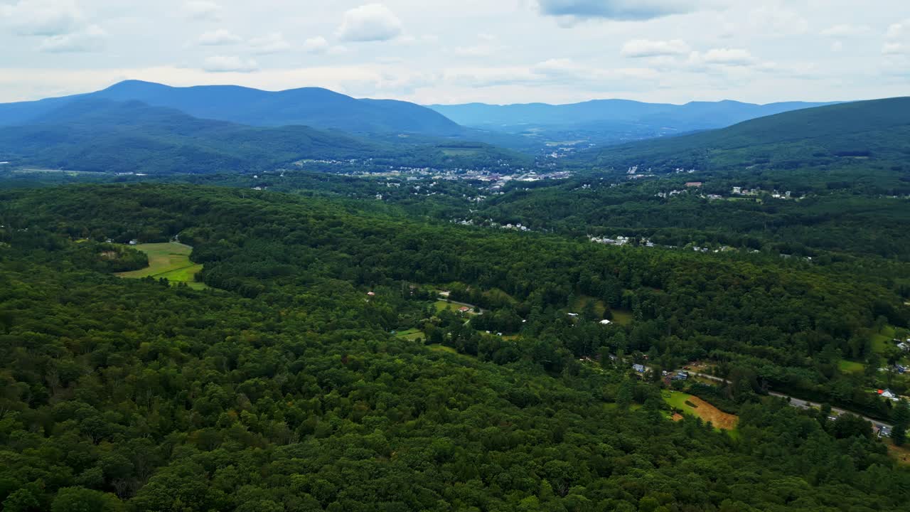 Panorama drone view of the distant Lee small town in vast mountain valley between dense forest, Berkshire, Massachusetts, USA