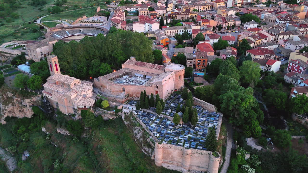 Drone performs an orbit around the historic walled cemetery in Brihuega, Spain, revealing gravestones, ancient walls and the surrounding village under soft morning light at sunrise