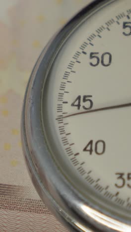 stopwatch with euro banknotes on background
