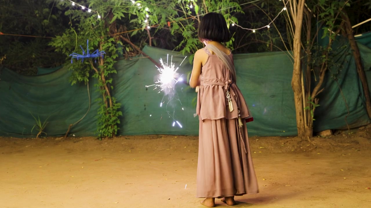 Bambina che celebra Diwali con una stellina luminosa sotto luci festive durante una celebrazione serale