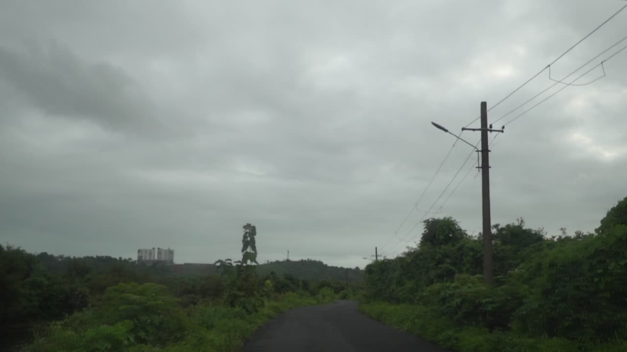tiro pov viajando a lo largo de un camino de alquitrán en un día húmedo y lluvioso, el camino rodeado de una espesa y exuberante vegetación tropical, panjim, india