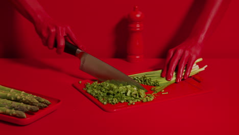 wide shot of beautiful red woman hands cutting leeks with knife on board.