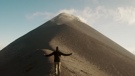 scenic landscape of a tourist hiker running towards the ridge of fuego volcano during daytime in guatemala