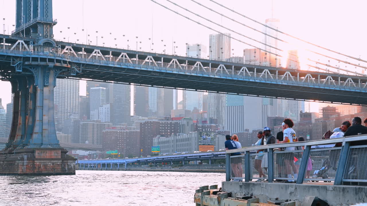 New York, USA, 8 luglio 2025: persone arrivano al molo sull'East River a New York, USA. Vista dal basso angolo del Manhattan Bridge e dello skyline metropolitano sullo sfondo