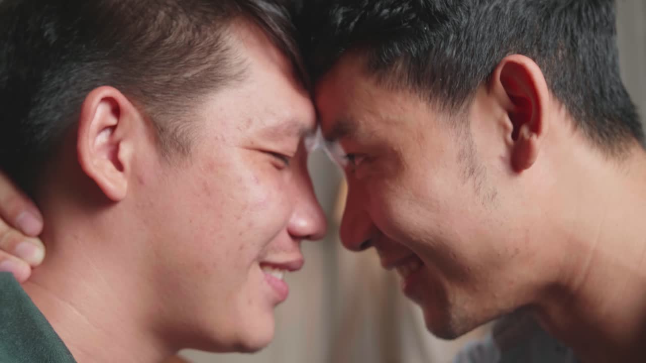 Close Up Of A Handsome Young Adult Gay Couple Spend Time At Home. Two Happy Men In Love In Casual Clothes Make A Gentle Headbutt. Cute Lgbt Relationship Content
