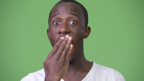 young african man shocked while covering face
