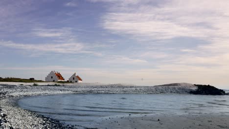 White houses on a pebble beach by the sea under a cloudy sky