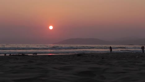 golden sunset over a silhouette of a island with ocean waves crashing, kids playing and birds flying past
