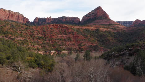 aerial: mountain valley with dry tree forest at sedona, arizona - drone flying forward shot