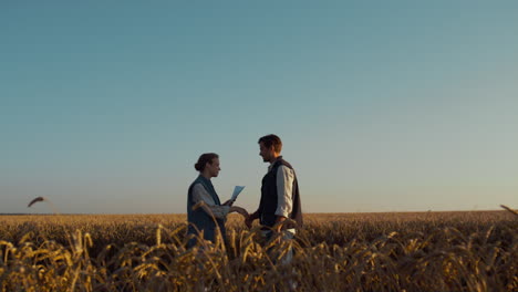 dos agricultores se reúnen con la luz del sol en el campo de trigo. un acuerdo de negocio agrícola exitoso.