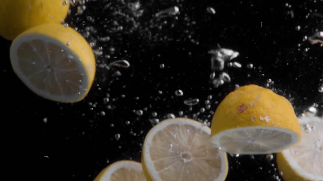 limones cayendo al agua en cámara superlenta, fondo negro, muchas burbujas de aire, 4k240fps