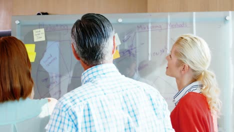 equipo de ejecutivos de negocios discutiendo sobre un tablero de vidrio