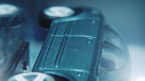 a little model metal toy car on a rotating stand with studio lights, vertical macro close up shot, 4k video, silver wheels, black tires, doors and windows