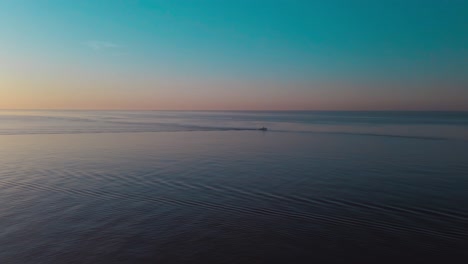 fly over sea water, lone motorboat during fire sunset