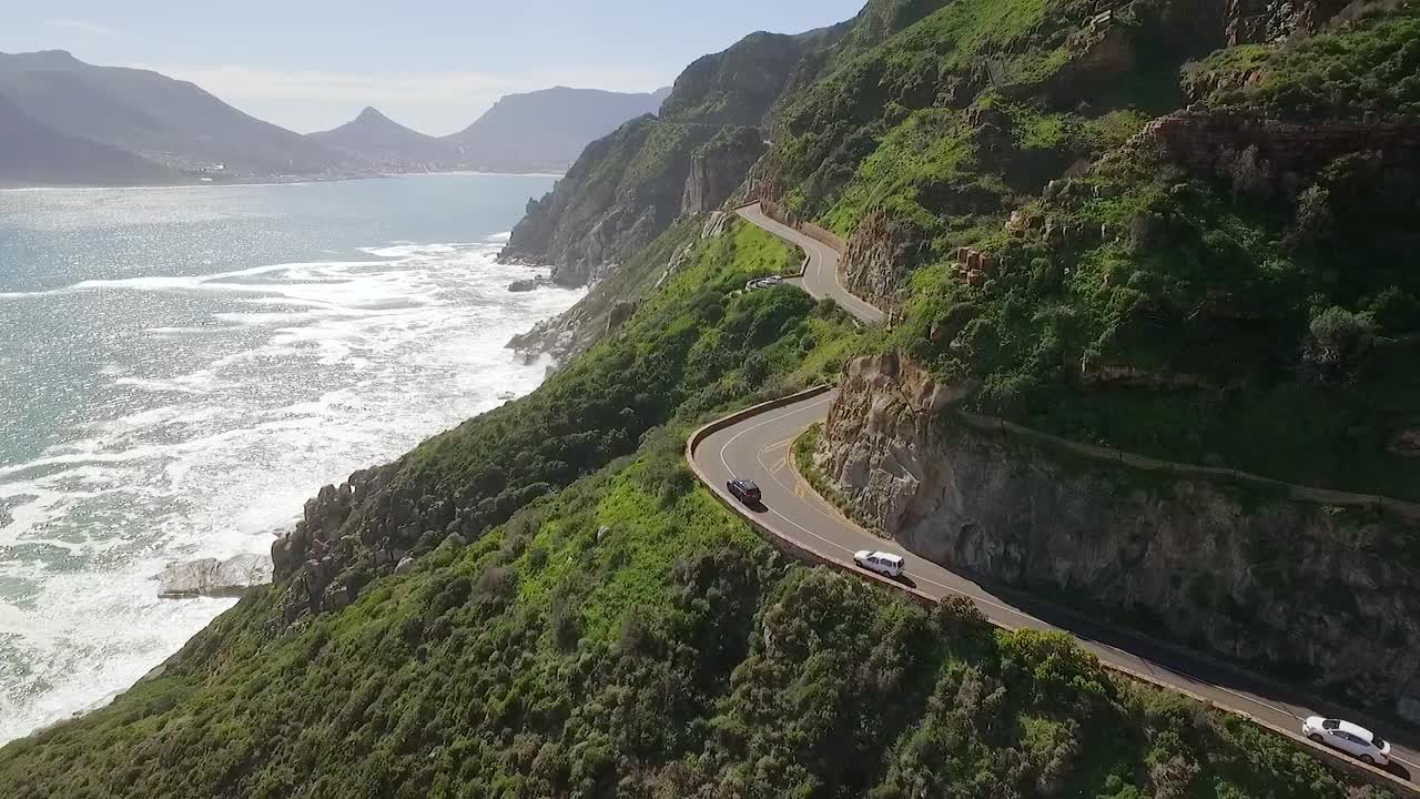 조감도는 자동차가 남아프리카 1의 채프먼 피크를 따라 해변에서 운전하는 것을 보여줍니다.